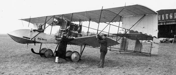 Tidligt Otto-biplan med besætning foran en hangar